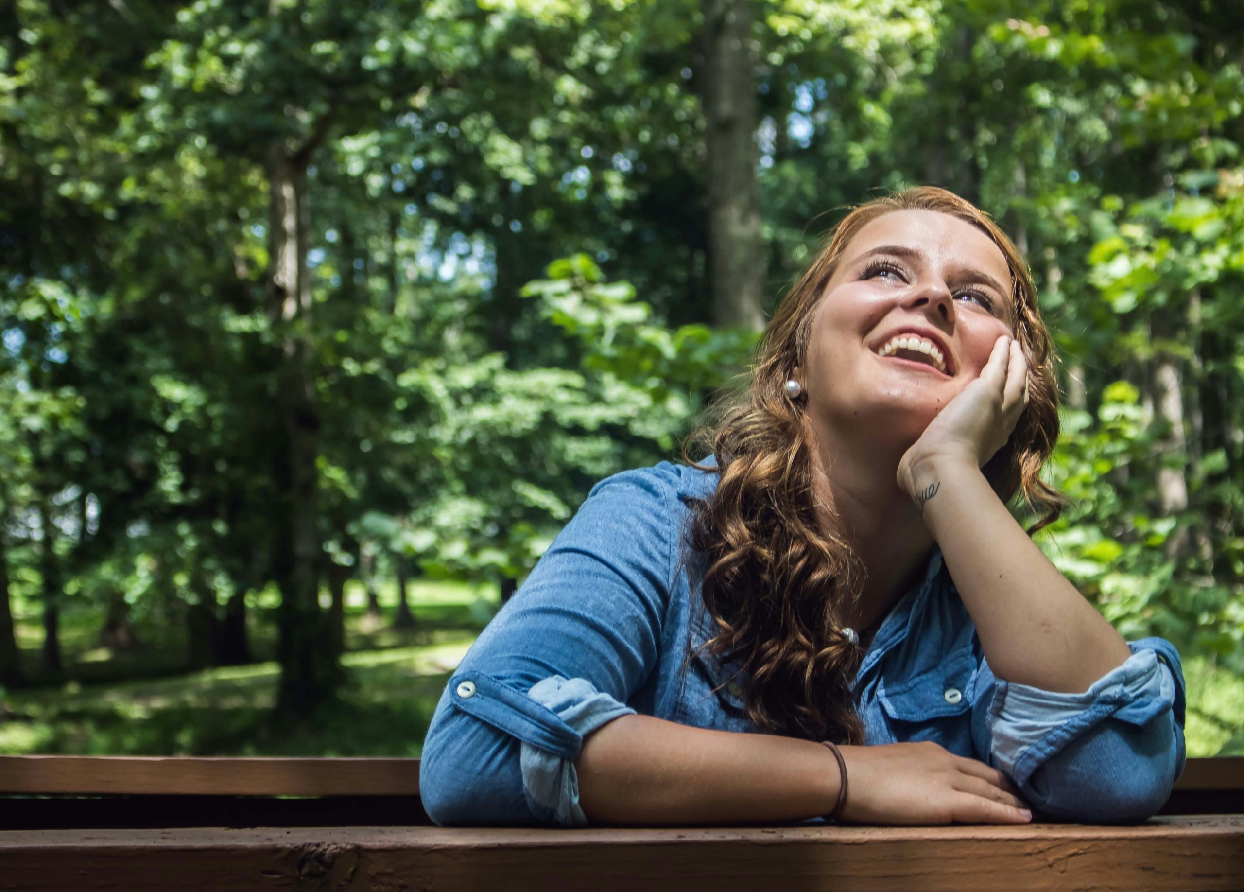 Mujer sonriente en un entorno natural, reflejando bienestar emocional, calma y equilibrio interior, representando los beneficios de la psicología positiva y el autocuidado.